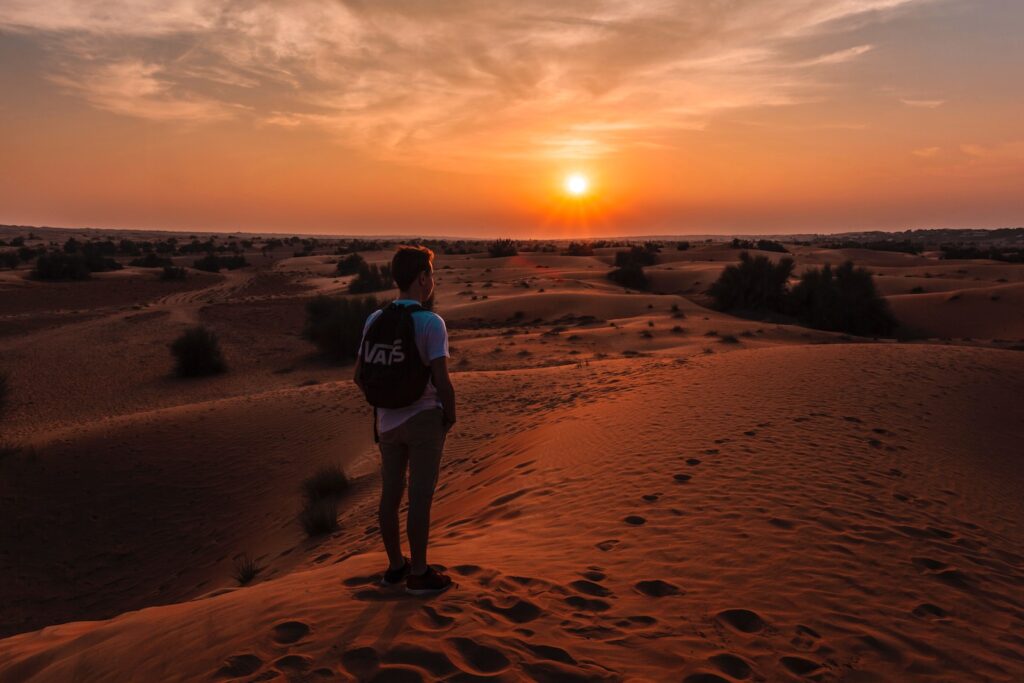 golden hour photography of man standing on top of a hill